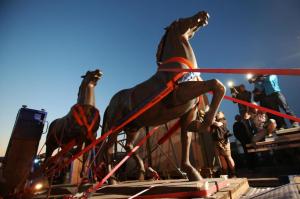 Two bronze horse statues by artist Josef Thorak are transported on a flatbed trailer in Bad Duerkheim, southwestern Germany, Thursday, May 21, 2015. A German investigation into black market art had recovered the two statues that once stood in front of Adolf Hitler's grand chancellery building in Berlin as well as other Nazi-era pieces that had been lost for decades. Police in five states conducted coordinated raids during more than a yearlong investigation into illegal art trafficking. (Fredrik von Erichsen/dpa via AP)